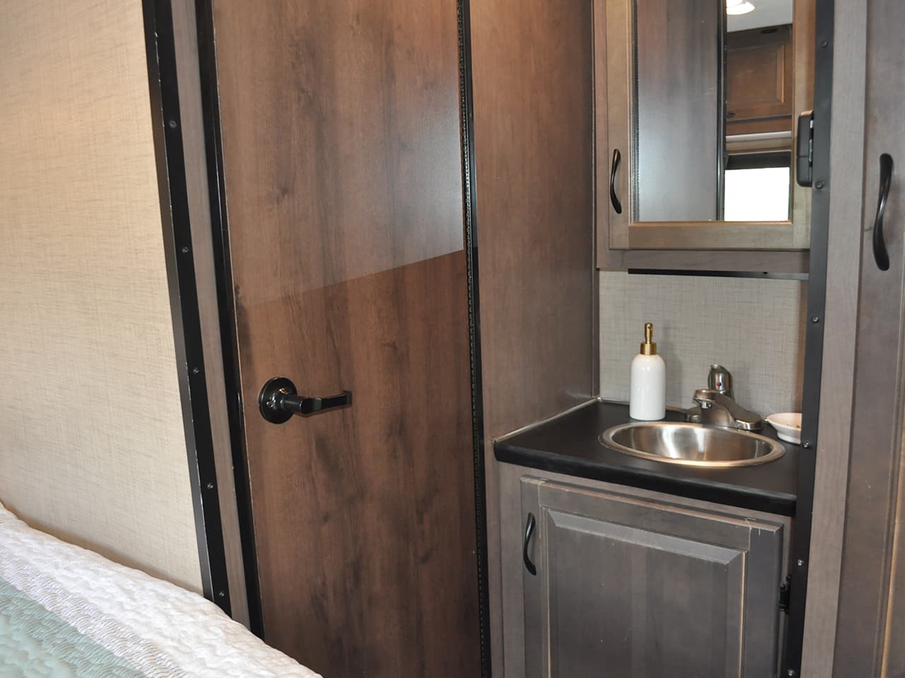 Bathroom sink area with mirror, and closed door to shower