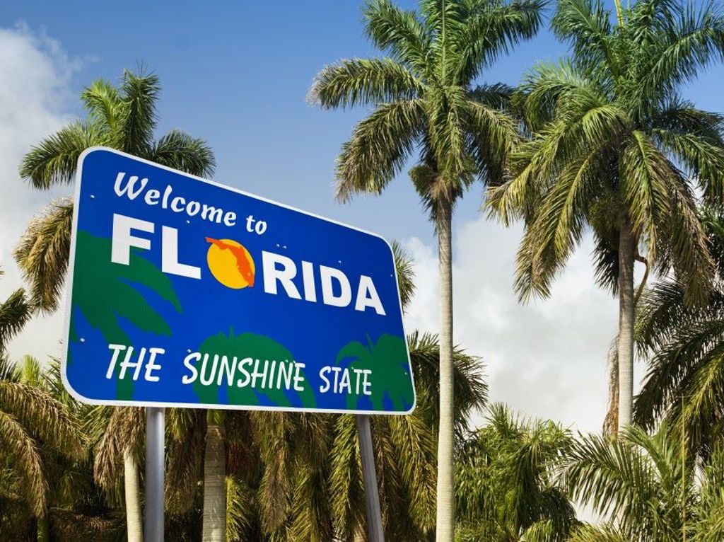 Sign that says welcome to Florida, in front of palm trees