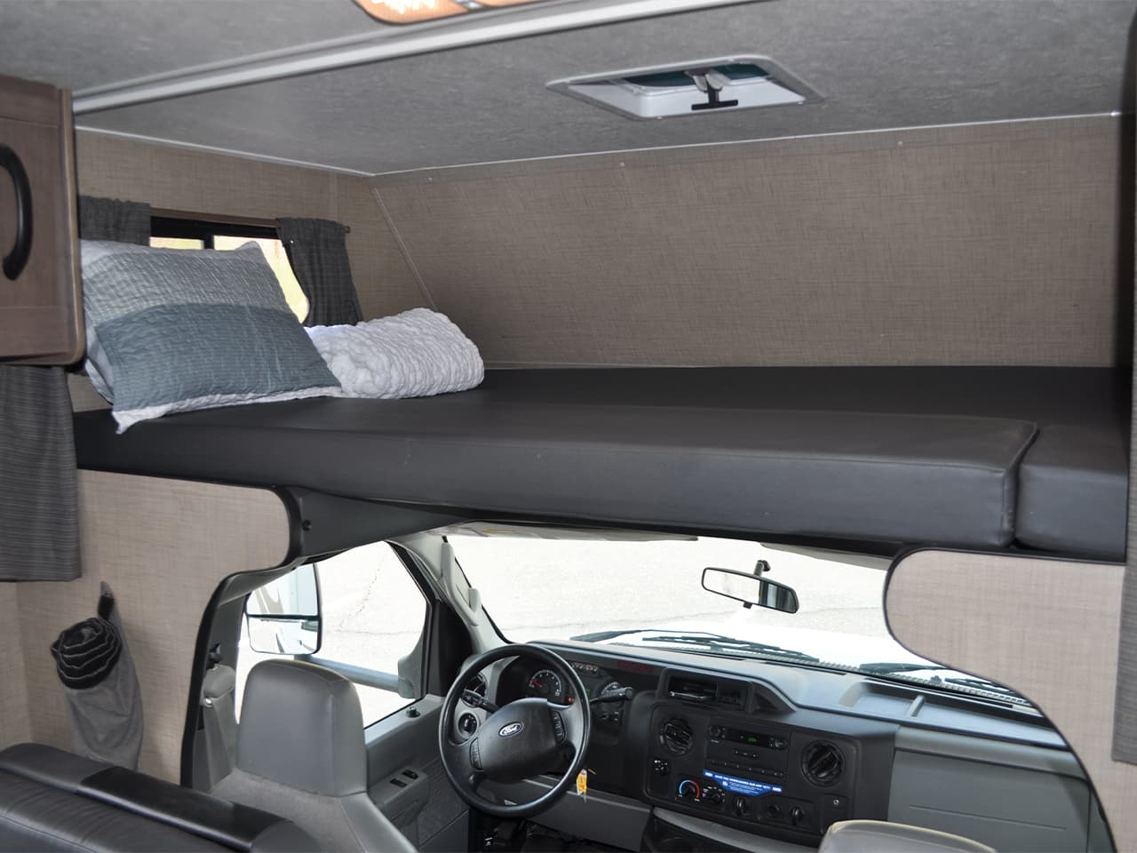Storage area above driver and passenger seats converted to a bed with a pillow
